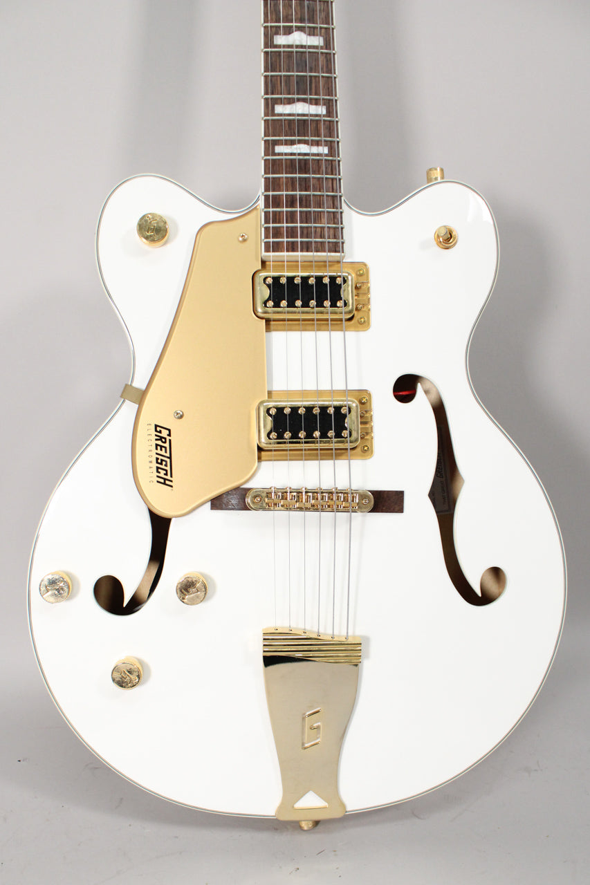 The white hollow body guitar is angled slightly, showing its gold hardware, f-holes, and dark fretboard with block inlays.