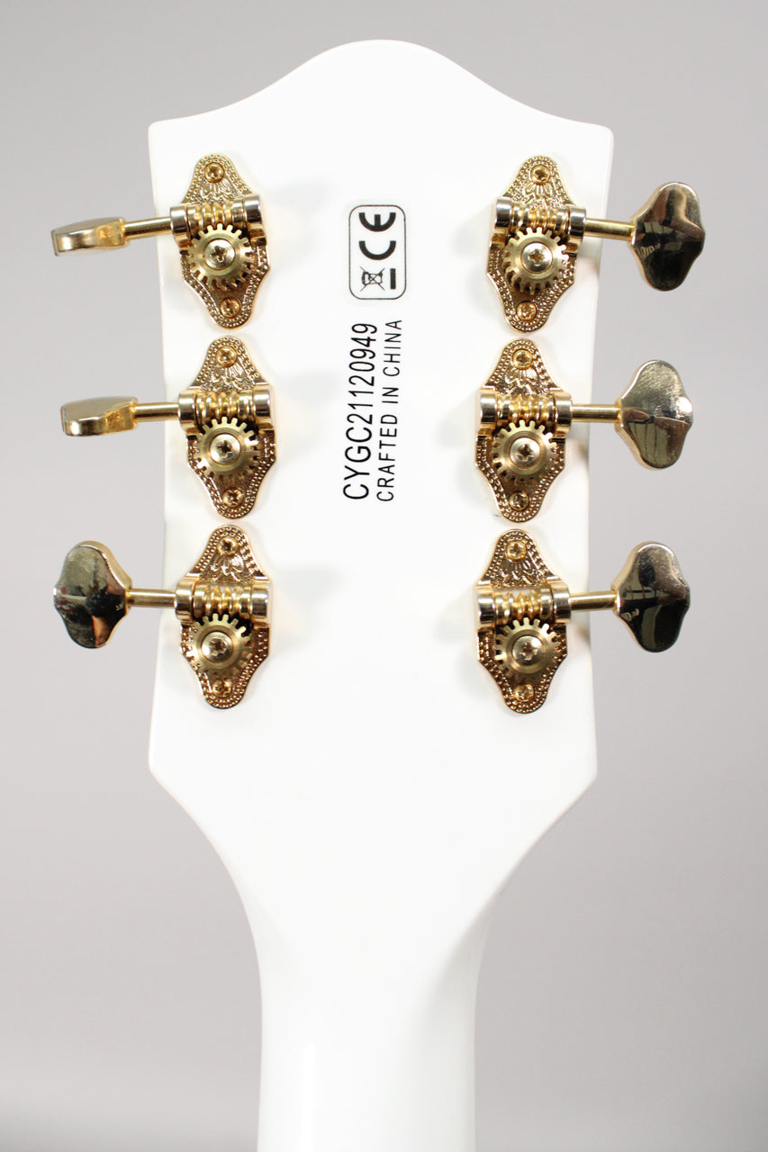 The back of a white headstock with six gold-plated, open-gear tuners, three on each side, showing light wear.