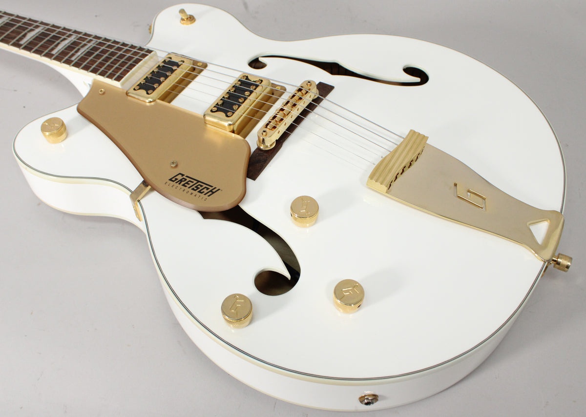Upper body of a white hollow-body electric guitar with gold hardware, f-holes, and a gold pickguard, shot from above.