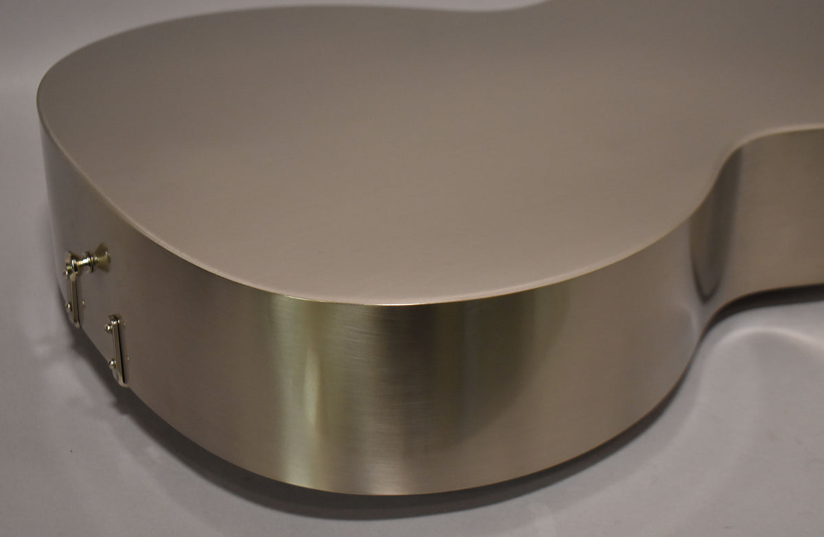 Close-up of a brushed metal guitar body, showing the lower bout and part of the side with two strap buttons.