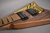 Close-up of the guitar body, showing the dark wood grain, gold hardware, black humbuckers, and light wood neck.