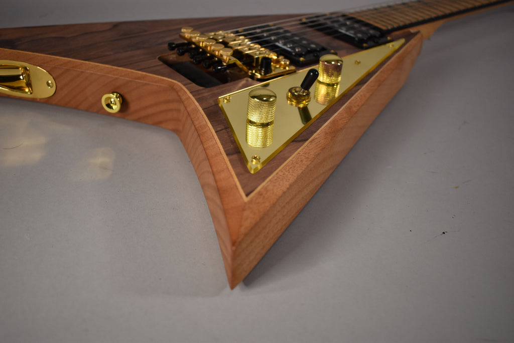 Close-up of the V-shaped body, showing the dark wood top, natural wood sides, and gold hardware on a gold control plate.