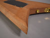 Close-up of the Rhoads' natural wood body, showing the sharp V-wing tip, black control cavity cover, and gold hardware.