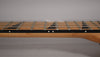 Close-up of the guitar's light brown maple neck and dark fretboard with black sharkfin inlays and white side dots.