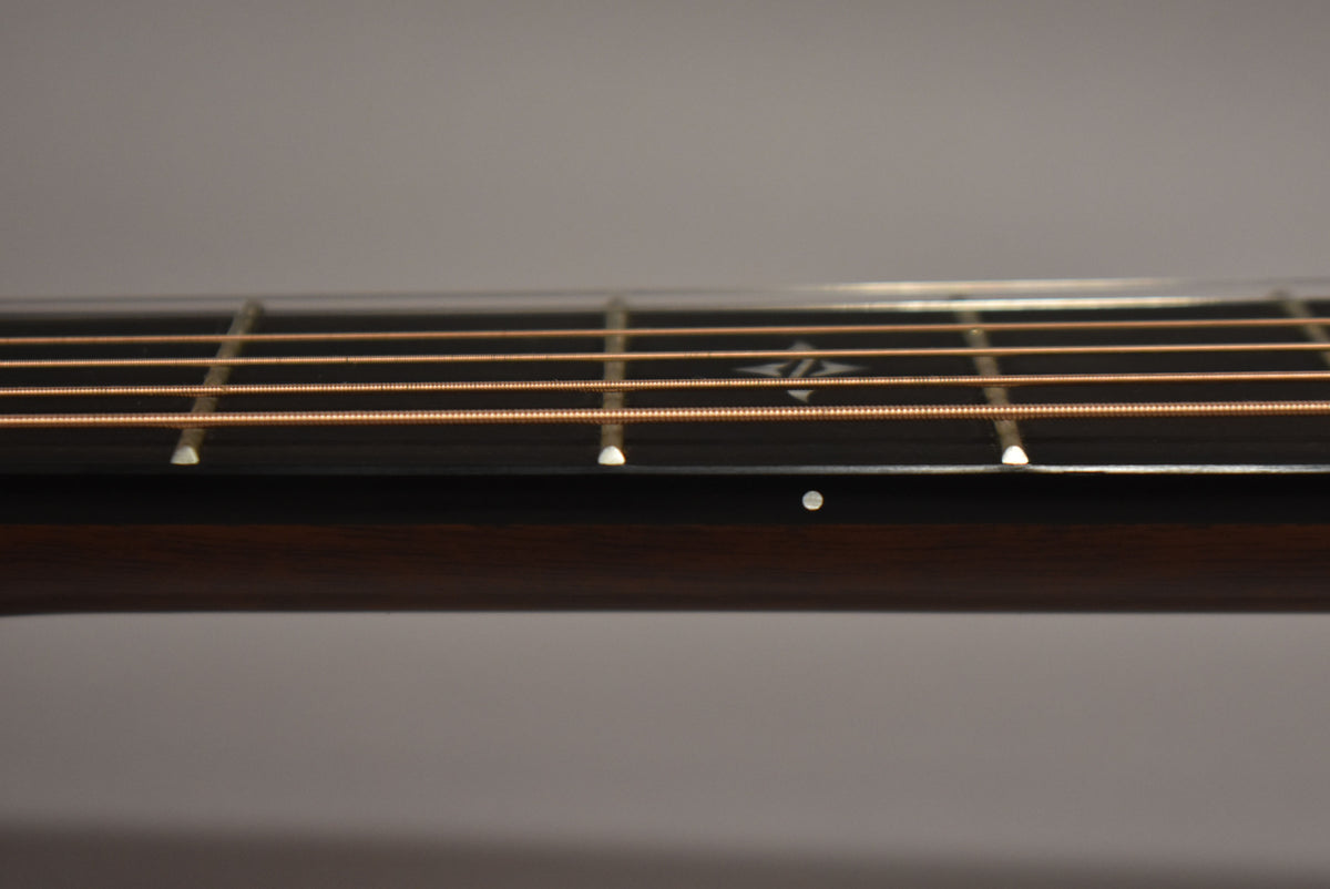 Close-up of the dark fretboard with copper strings, showing a diamond inlay at the 7th fret and a white side dot.