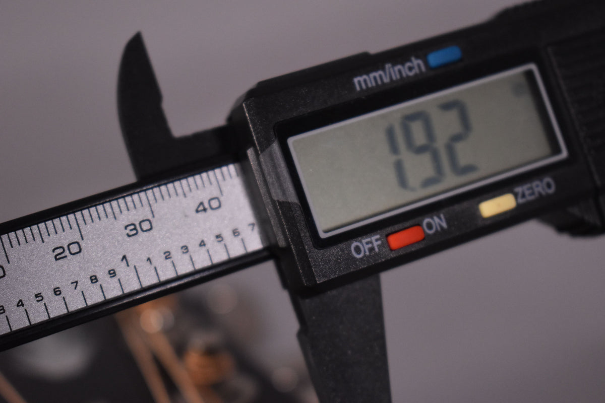 A digital caliper shows a reading of 19.2, with a ruler marked 20, 30, 40 mm visible.