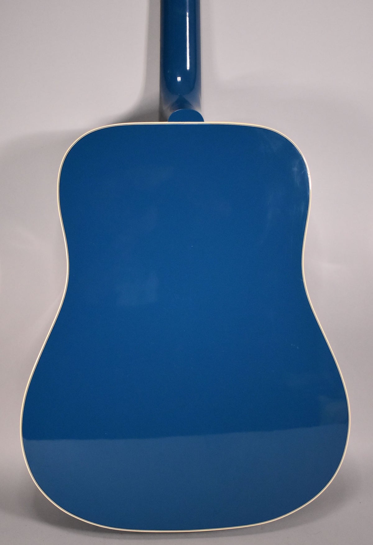 The back of a Big Sky Blue acoustic guitar, with a glossy finish and cream binding, showing the neck joint.