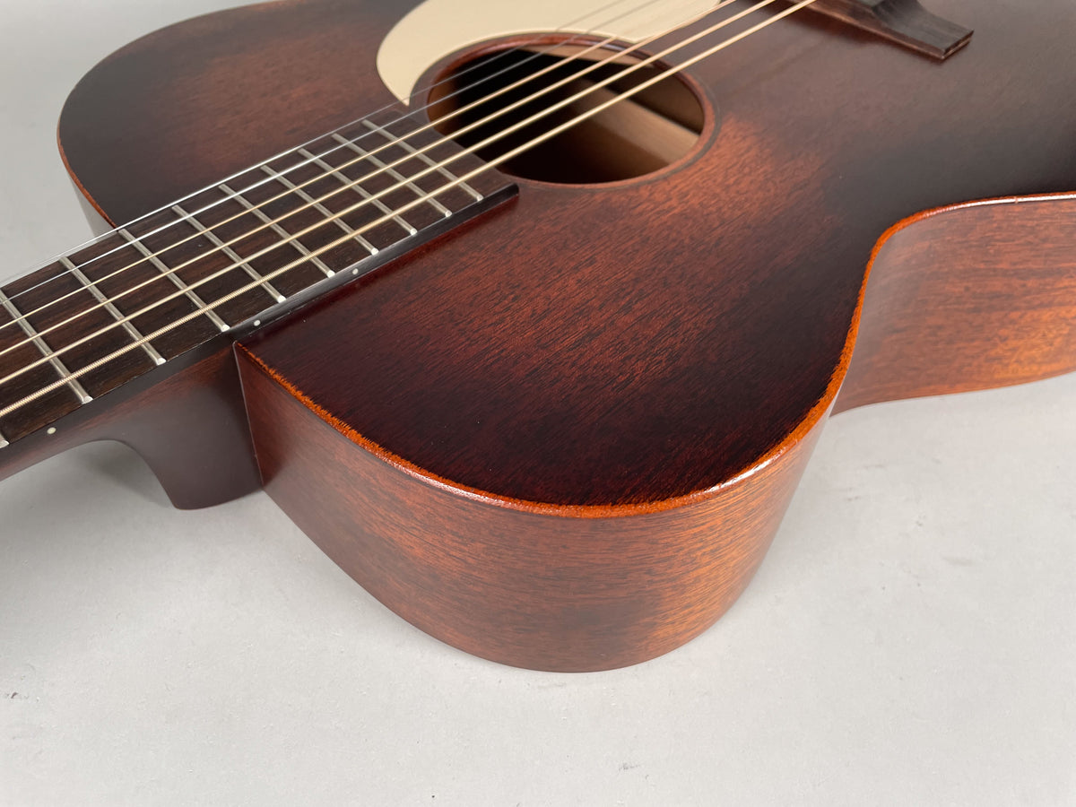 Close-up of the dark brown acoustic guitar's lower bout and fretboard, showing a satin finish and light brown binding.