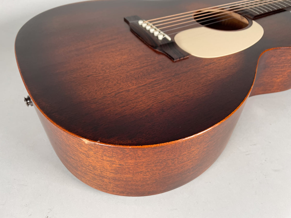 Close-up of the dark brown acoustic guitar body, showing a small chip on the lower bout and a strap button on the side.
