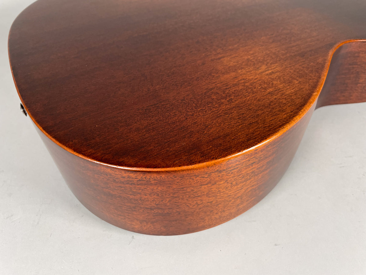 Close-up of the dark brown satin-finished acoustic guitar's lower bout and side, showing the wood grain.