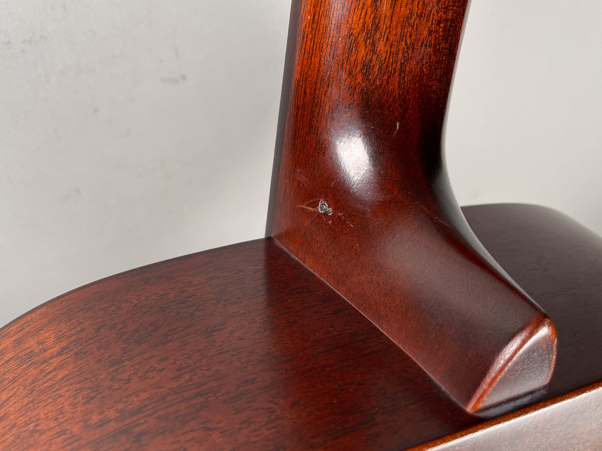 Close-up of the guitar's dark brown neck heel and body, showing a small chip and several scratches on the neck.