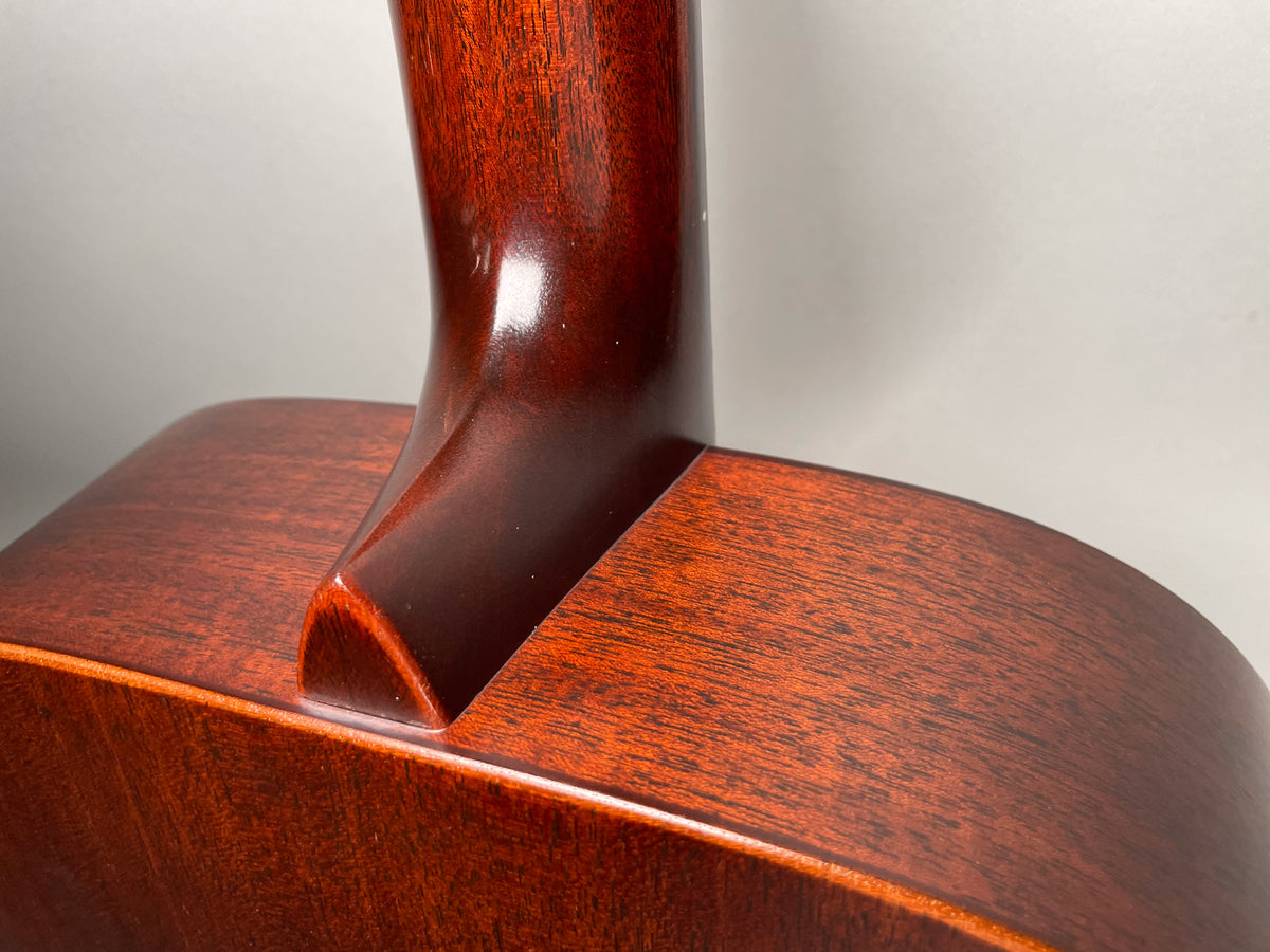 Close-up of the guitar's dark reddish-brown neck heel and body, showing the wood grain and a subtle satin finish.
