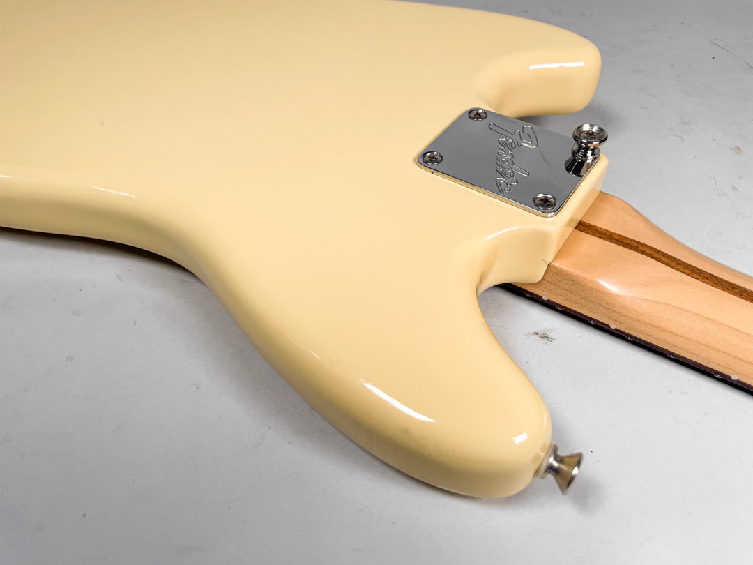 The back of a cream-colored guitar body, showing the chrome neck plate, strap button, and the light wood neck with dark stripes.