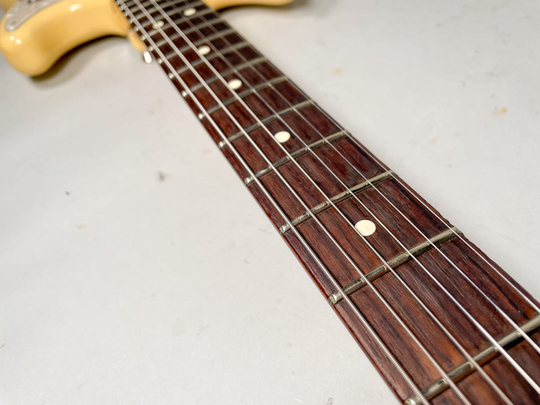 Close-up of the guitar's dark rosewood fretboard with white dot inlays and metal frets, angled from the body towards the headstock.