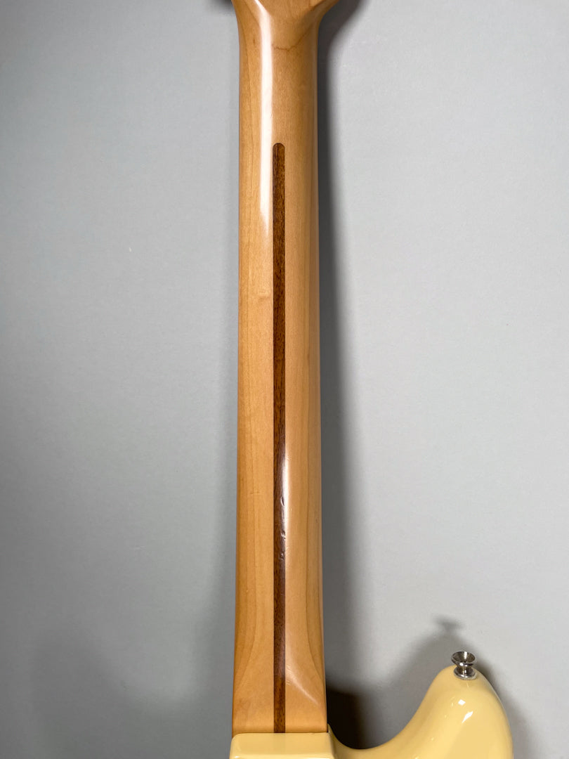 The back of a light-colored maple neck with a dark walnut skunk stripe, joining a creamy white body.