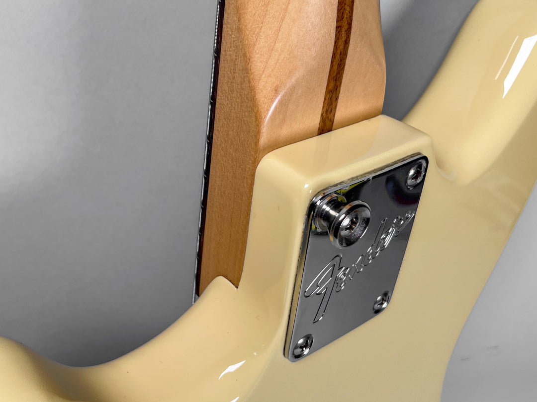 Close-up of the guitar's cream body and neck heel, showing the chrome neck plate with a strap button and four screws.