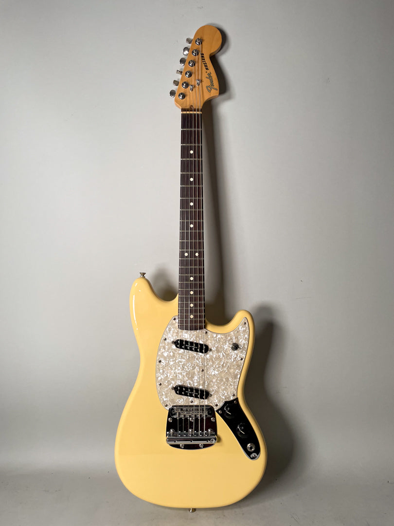 Full-length, front view of a pale yellow electric guitar with a pearloid pickguard, two black humbuckers, and a chrome tremolo.