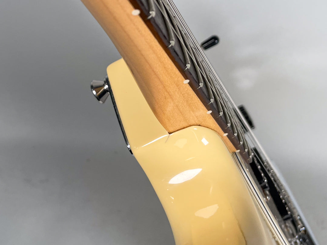 Close-up of the guitar's creamy body and maple neck joint, showing a small finish crack at the heel.