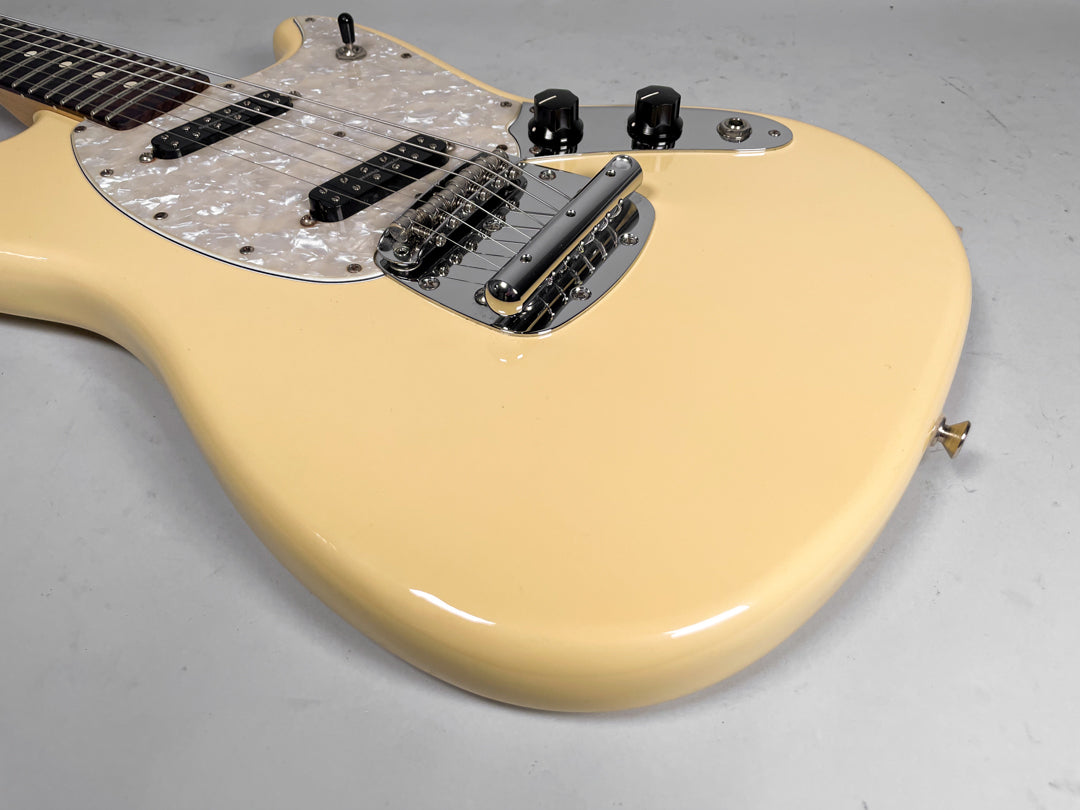 Cream-colored electric guitar, angled from the neck to the lower bout, with a pearloid pickguard and chrome hardware.