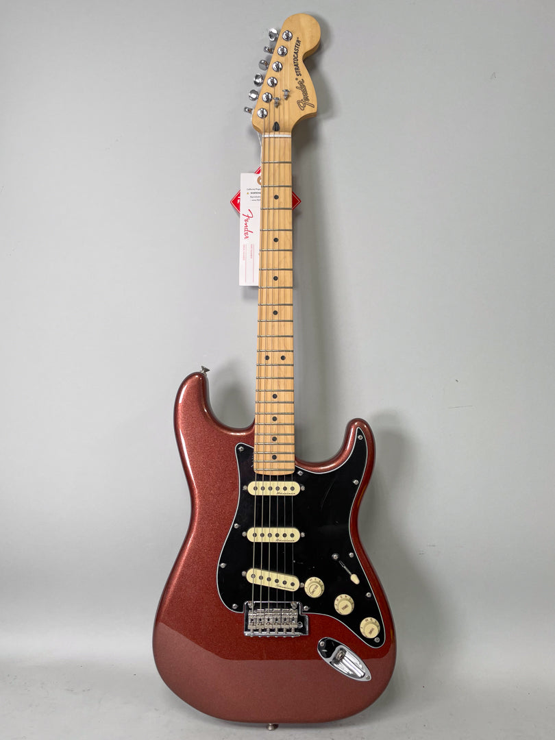 Full-length view of a metallic copper Stratocaster with a black pickguard, three cream single-coil pickups, and a maple neck.