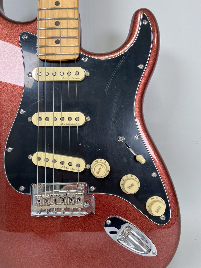A close-up of the copper sparkle Stratocaster body, showing the black pickguard with three cream single-coil pickups and controls.