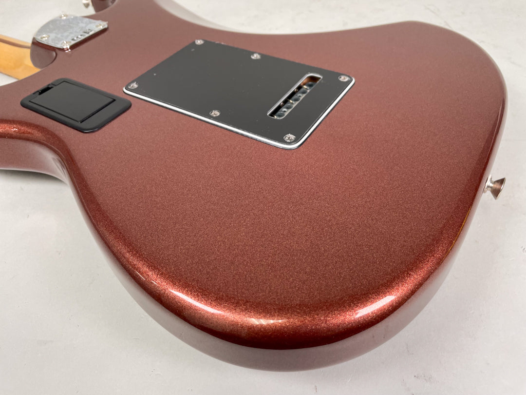 The guitar's classic copper metallic finish is shown from the back, revealing a black tremolo cavity cover and battery compartment.