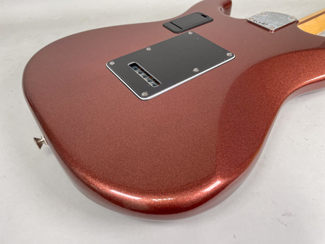 The guitar's classic copper metallic finish is seen from the back, showing the tremolo spring cover and neck plate.