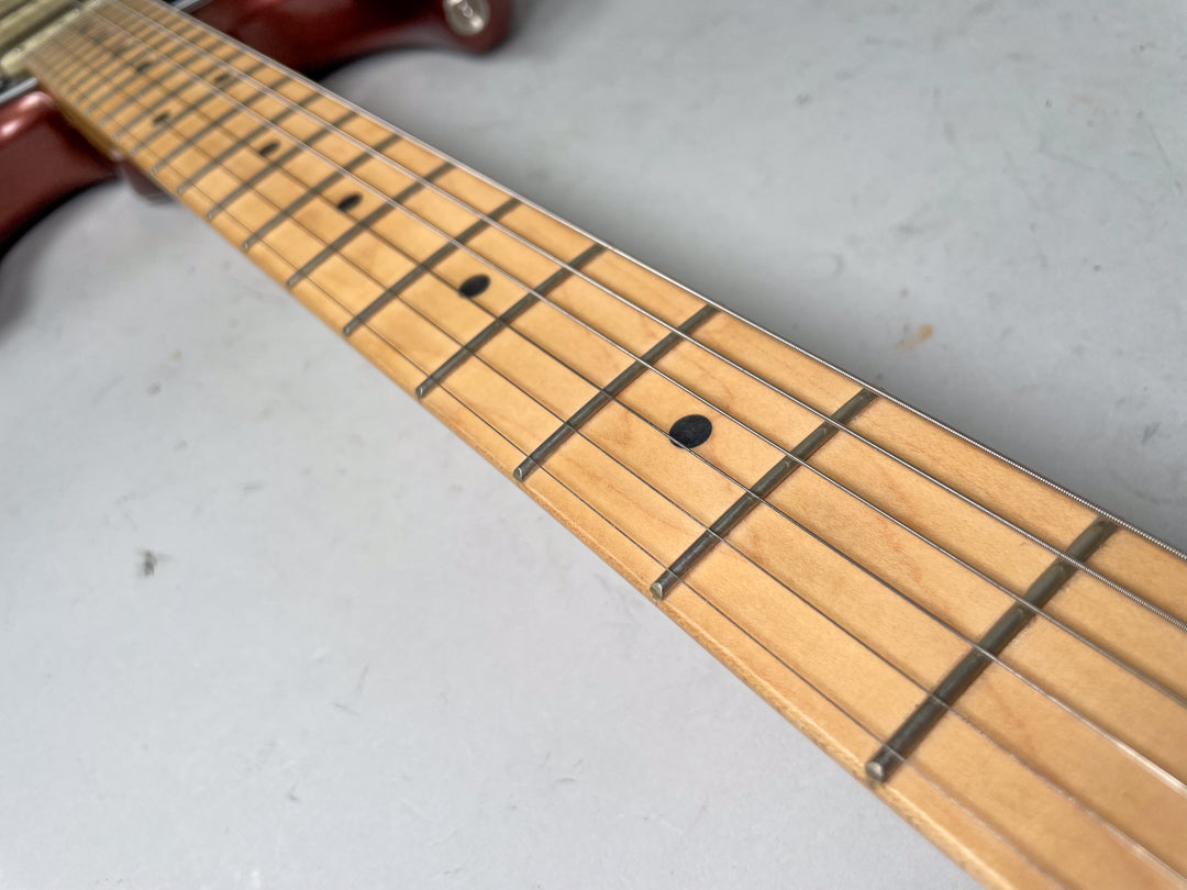 Close-up of the maple fretboard, angled from the headstock, showing black dot inlays and light string wear on the frets.