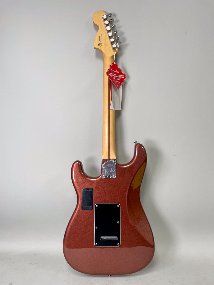 Full rear view of a metallic copper Stratocaster with a maple neck, chrome tuners, and a black backplate and battery compartment.