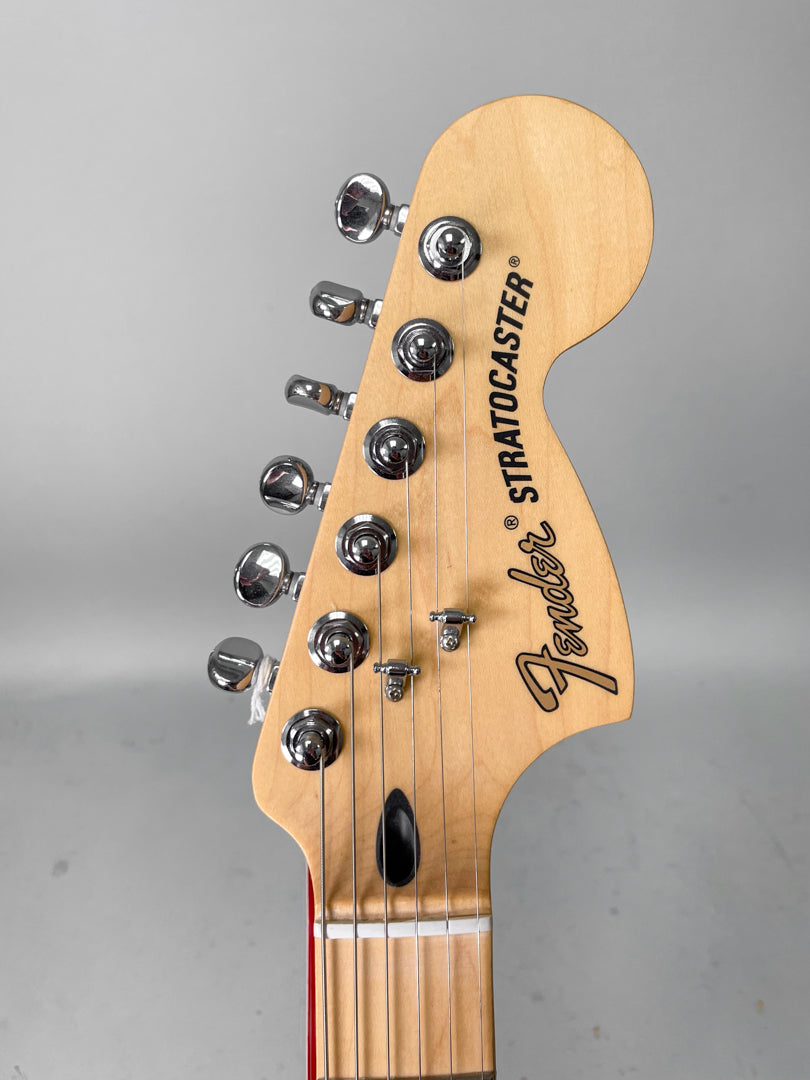 The guitar's light wood headstock, with six chrome tuners and two string trees, is angled slightly left.