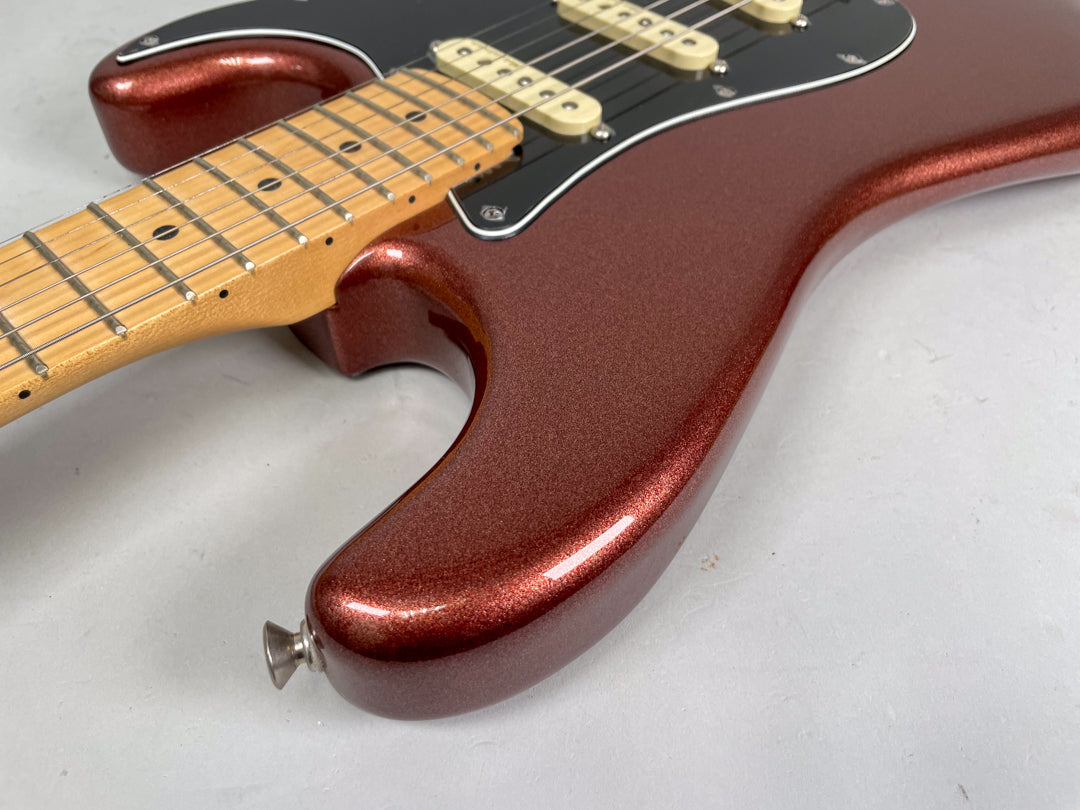 Upper body of a metallic copper Stratocaster, showing the lower horn, black pickguard, three cream pickups, and maple neck.