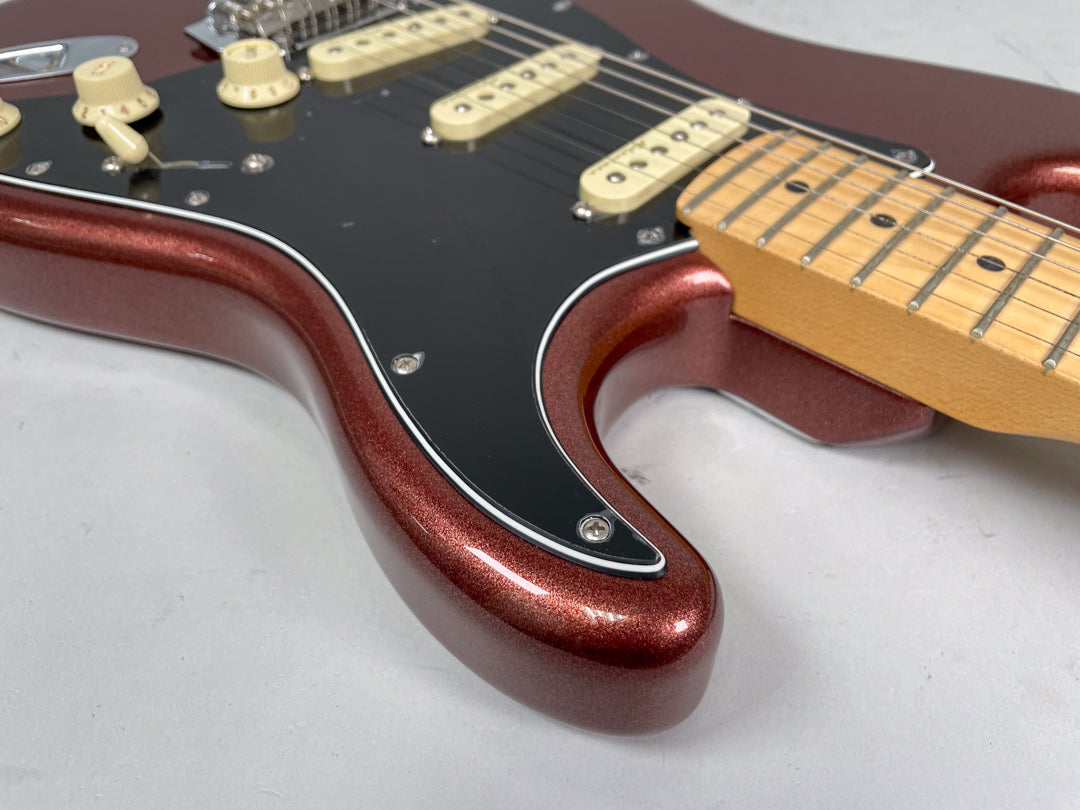 Close-up of the metallic copper body and black pickguard, showing cream pickups, knobs, and a maple fretboard.