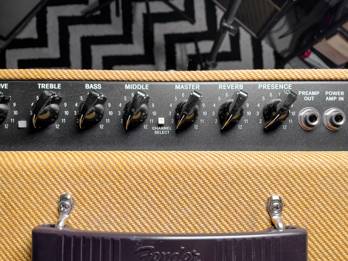 Close-up of the amp's black control panel with seven black chicken head knobs, two white push buttons, and two silver input jacks.
