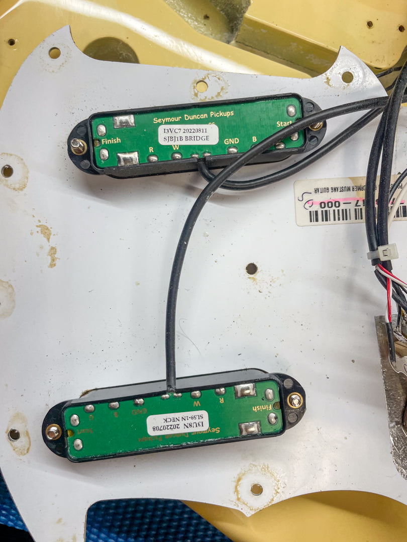 Close-up of the guitar's interior, revealing two green circuit boards of the Seymour Duncan pickups mounted on a cream pickguard.