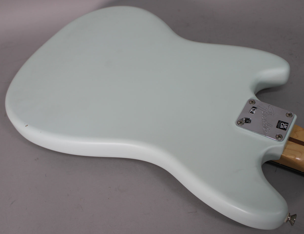 The back of a light blue Mustang guitar body, showing the neck plate and a small black mark on the lower bout.