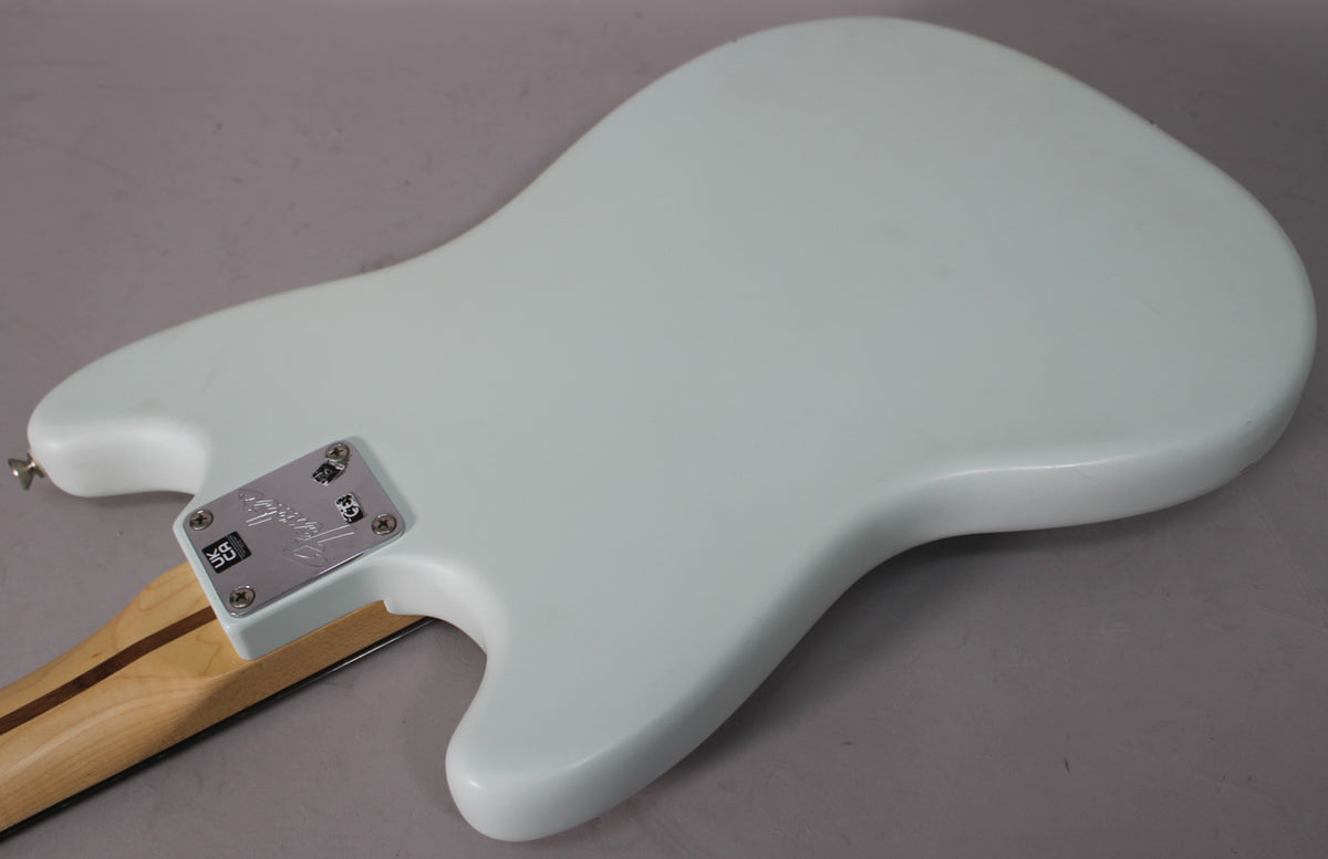The back of a light blue guitar body with a chrome neck plate and a maple neck with a dark stripe.