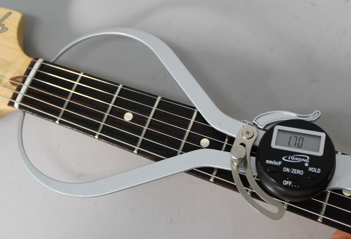 Close-up of the guitar's dark fretboard with white dot inlays, measured by a silver digital caliper displaying "1.70".
