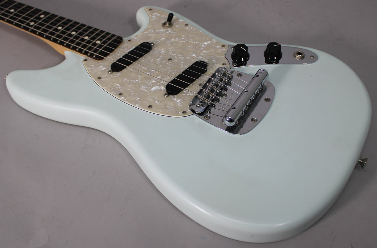 Light blue Mustang electric guitar body, angled from above, showing a pearloid pickguard, two black single-coil pickups, and chrome hardware.