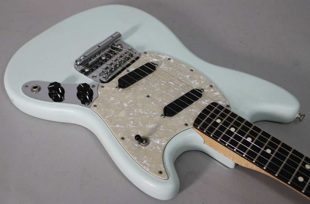 Light blue electric guitar body, angled from above, showing a pearloid pickguard, two black pickups, and chrome hardware.