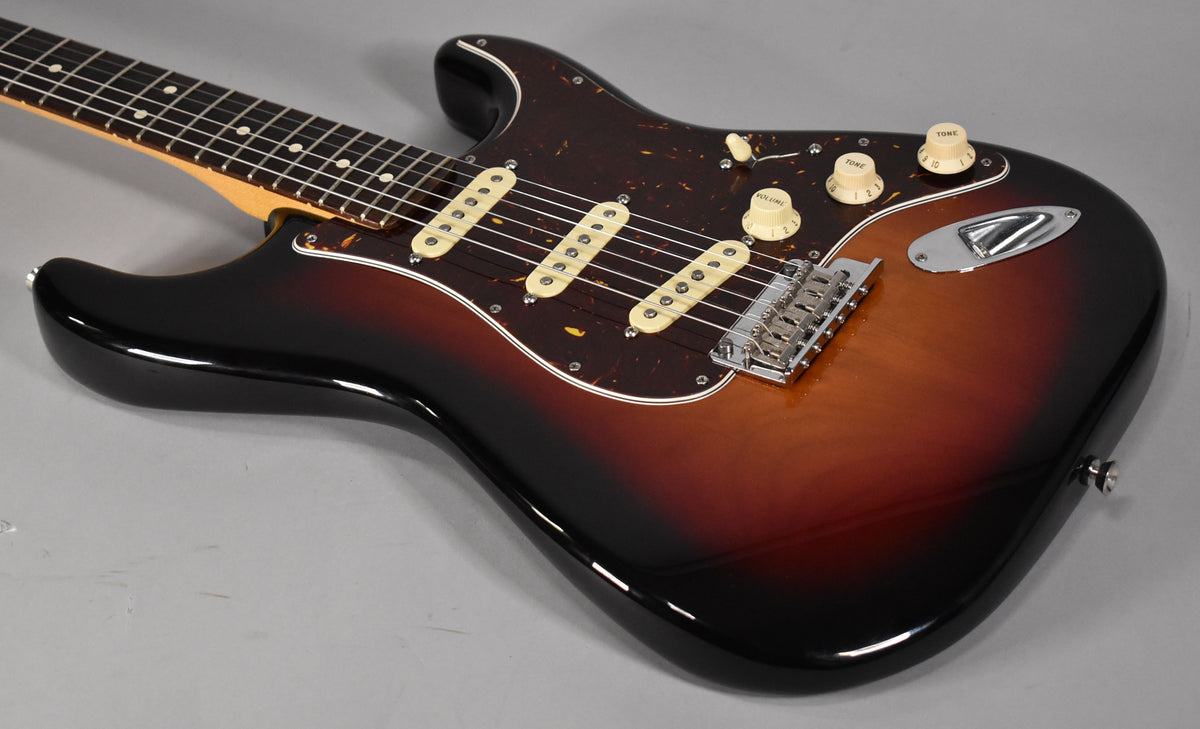 The sunburst Stratocaster, viewed from above, shows its glossy finish, tortoiseshell pickguard, three cream single-coil pickups, and chrome hardware.