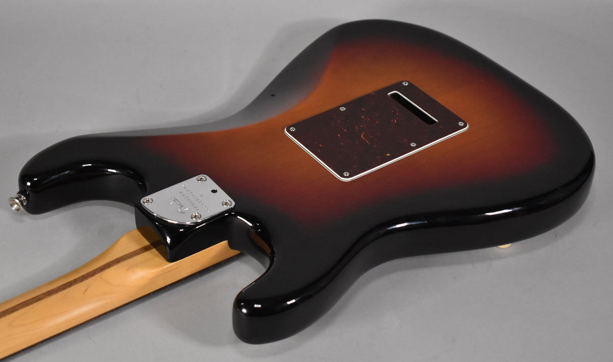 The back of a glossy sunburst Stratocaster body, angled from the lower bout, showing the neck plate and tremolo cavity cover.
