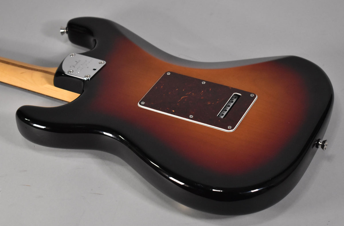 The guitar's sunburst back shows a tortoiseshell tremolo cover, chrome neck plate, and a light maple neck.