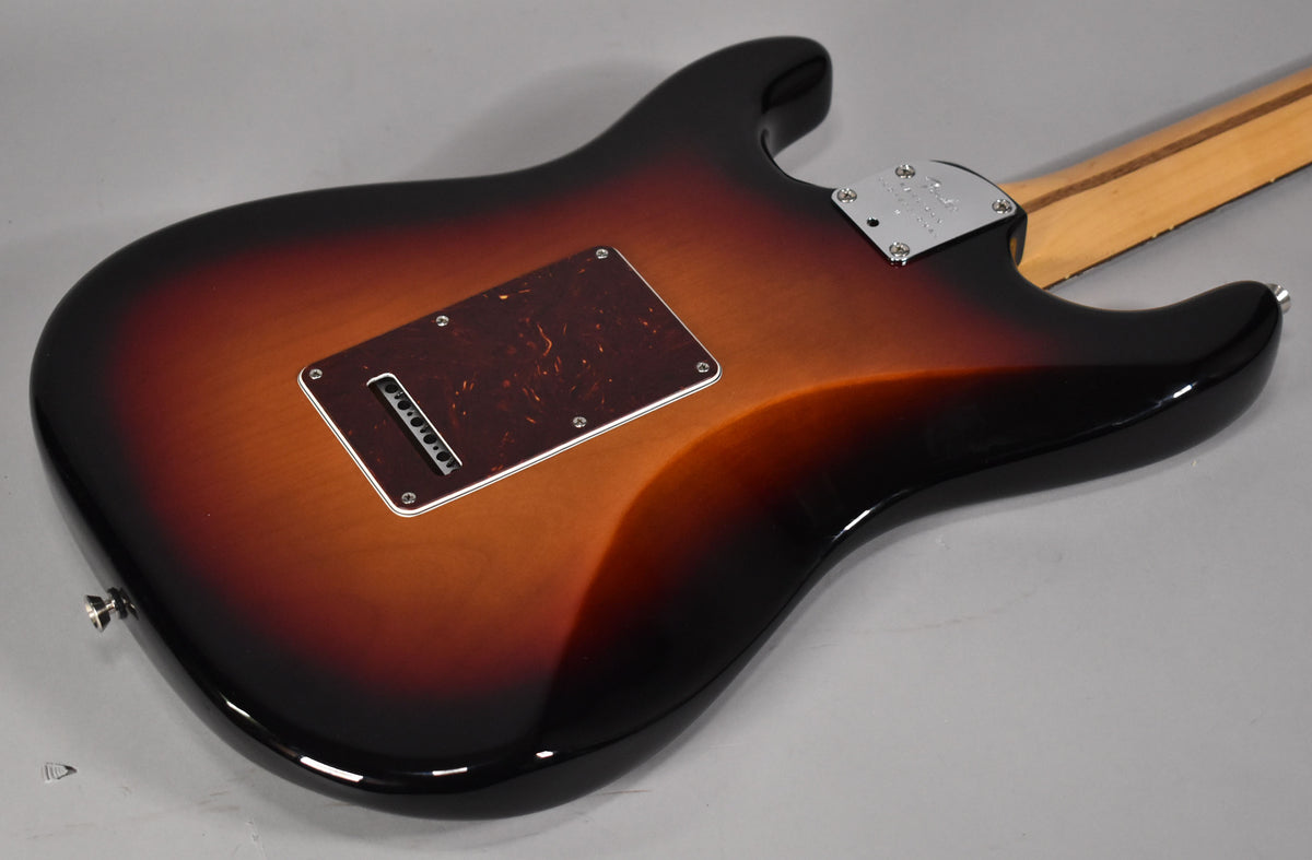 The back of a glossy sunburst electric guitar, angled to show the tremolo cavity cover and neck plate.