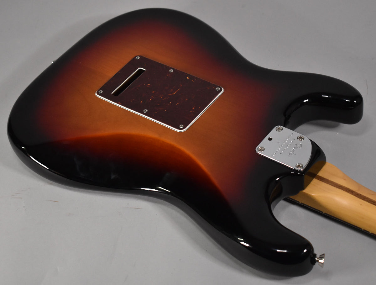 The back of a glossy sunburst Stratocaster body, showing the tremolo cavity cover, neck plate, and a light-colored maple neck.