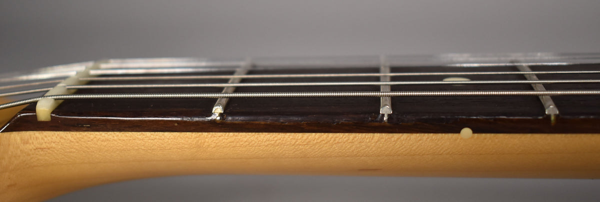 Close-up of the Stratocaster's dark rosewood fretboard and maple neck, showing the nut, frets, and a single side dot.