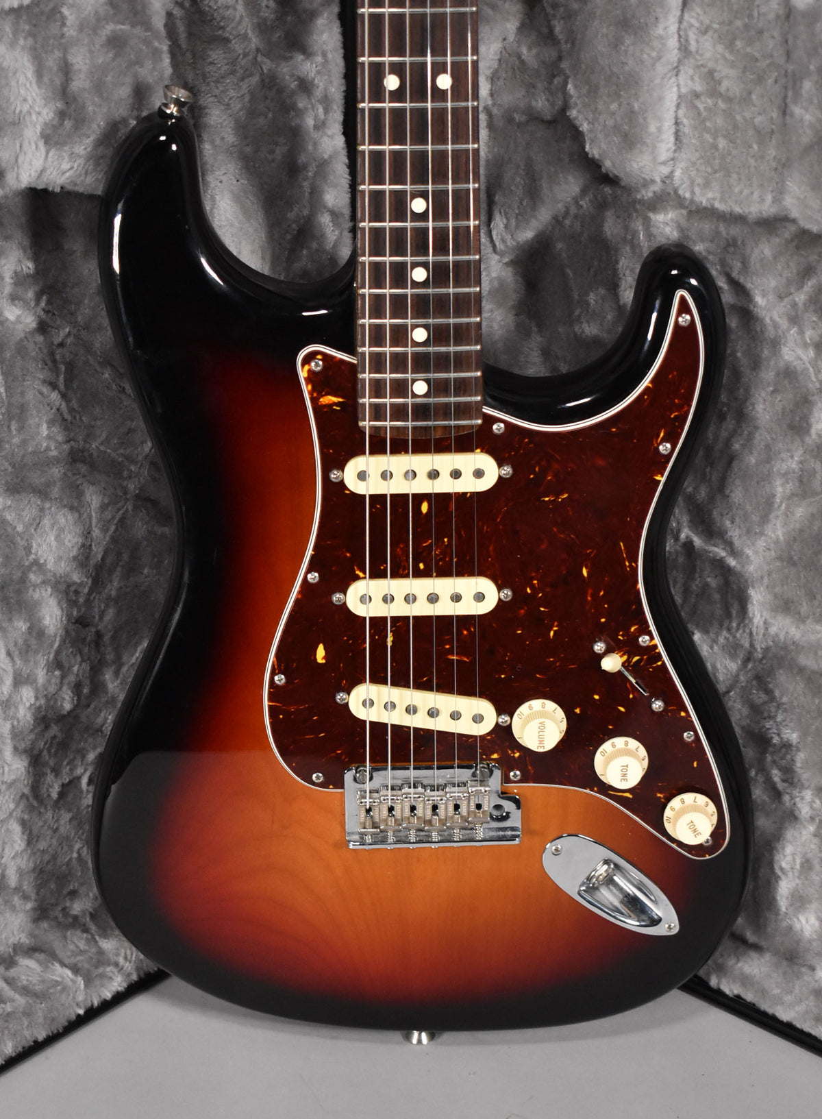 Full-frame view of a sunburst electric guitar with a tortoiseshell pickguard, three cream single-coil pickups, and chrome hardware.