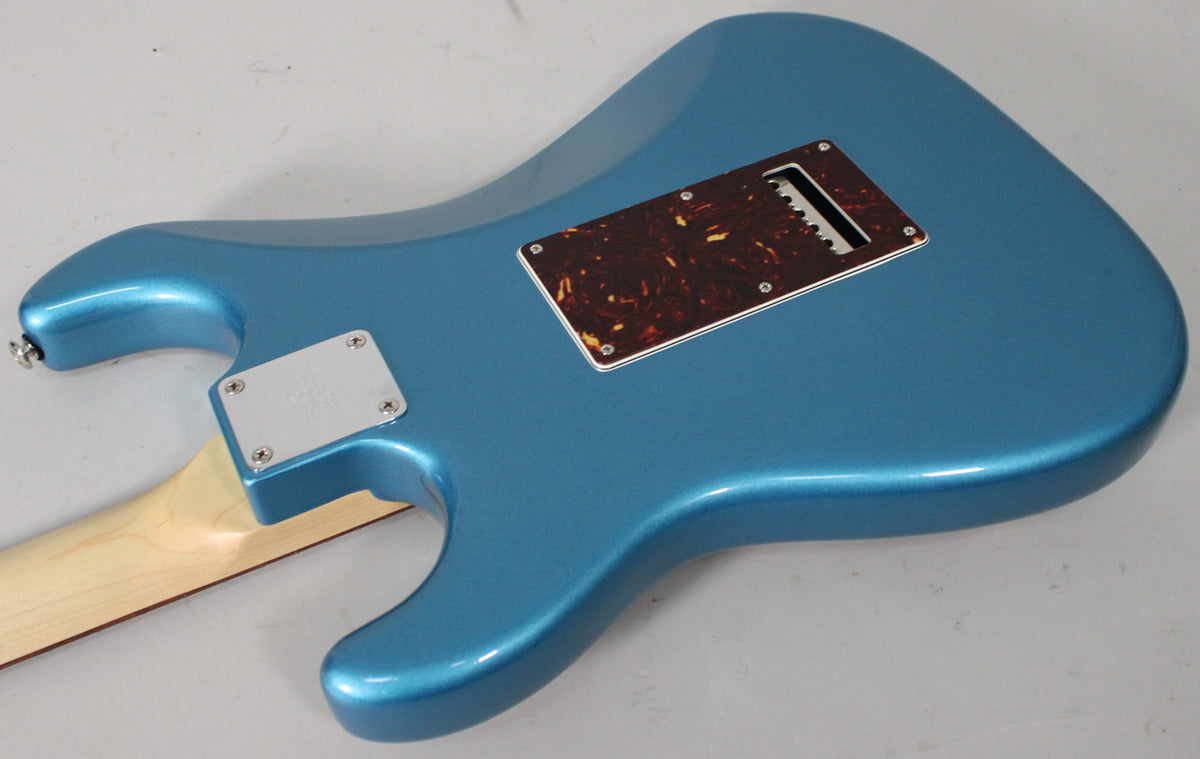 The back of a metallic blue guitar body, showing a tortoiseshell tremolo cover and a chrome neck plate.
