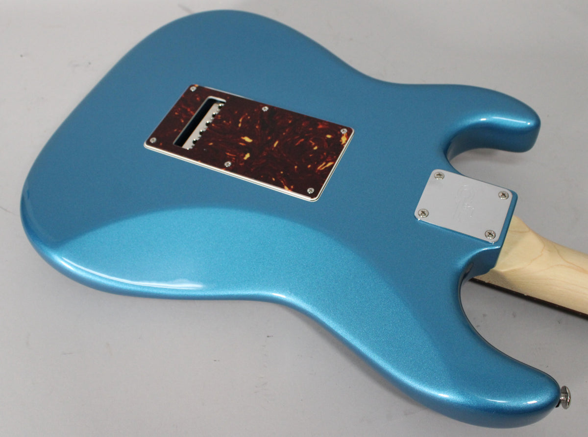 The back of a metallic blue electric guitar, angled to show the tortoiseshell tremolo cover and chrome neck plate.