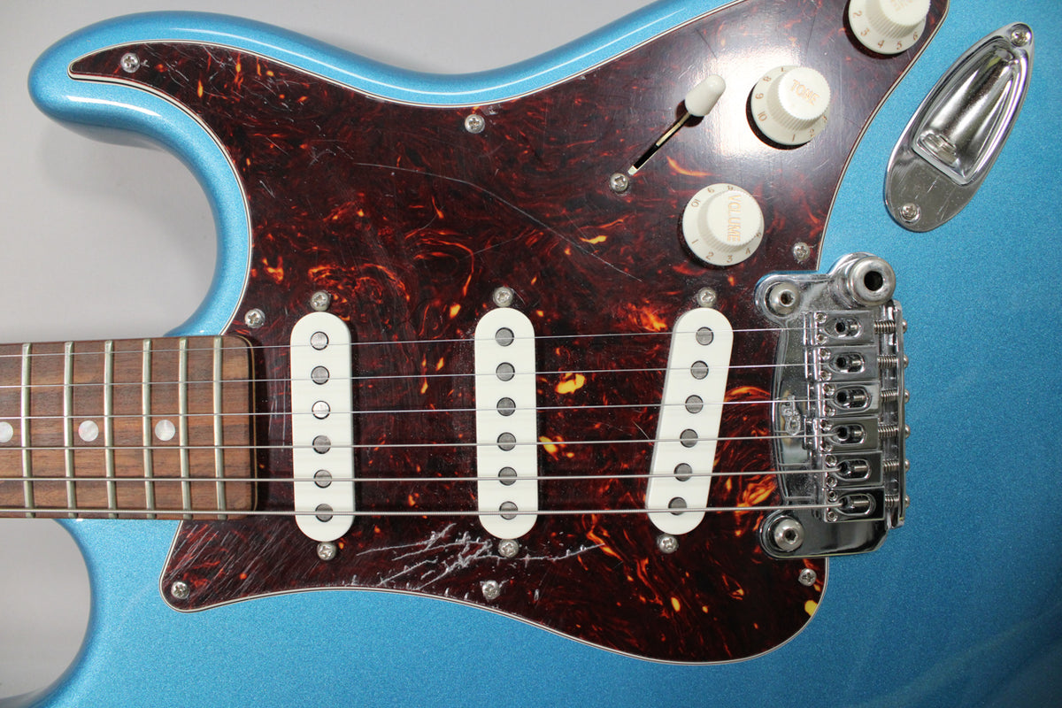 Close-up of the guitar's Lake Placid Blue body, tortoiseshell pickguard, three white single-coil pickups, and chrome tremolo bridge.