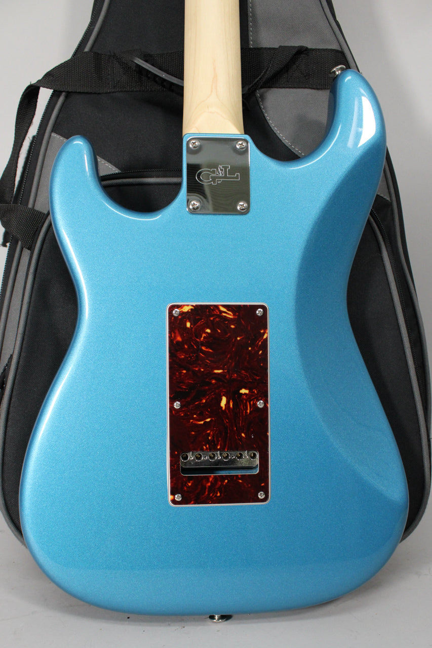 The metallic Lake Placid Blue guitar back, with a tortoiseshell tremolo cover and a maple neck, rests against a black gig bag.